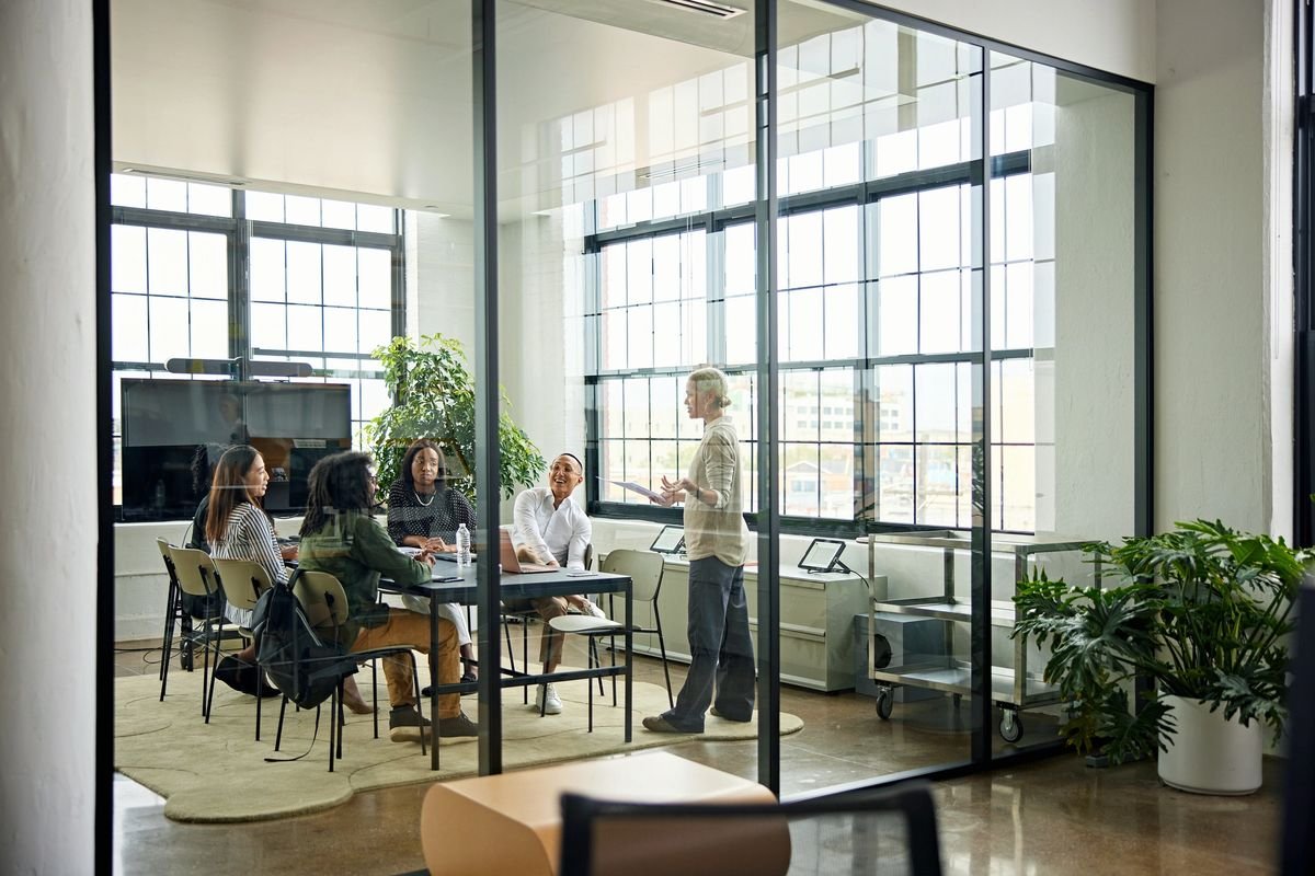 A group meeting in a modern office with large windows and glass walls